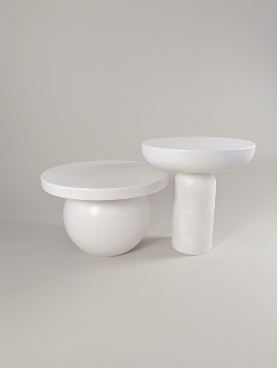 Stolik kawowy HARMONIA pokryty mikrocementem w kolorze neutralnej bieli. Blat okrągły zaoblony od spodu, noga tuba zaokrąglona od góry. Naturalna struktura, matowe wykończenie. Zdjęcie produktowe na neutralnym jasno beżowym tle. Zestaw ze stolikiem ENSO